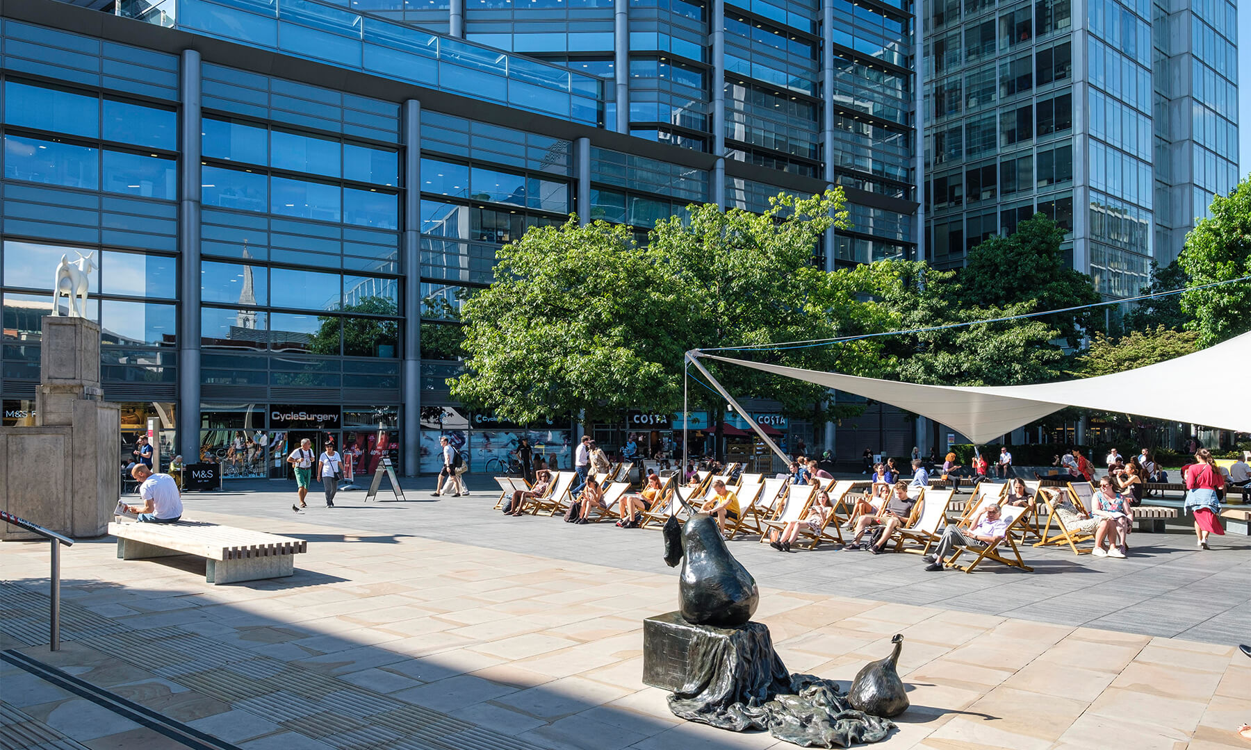 People lounging on deckchairs in the sun in Spitalfields Market. 