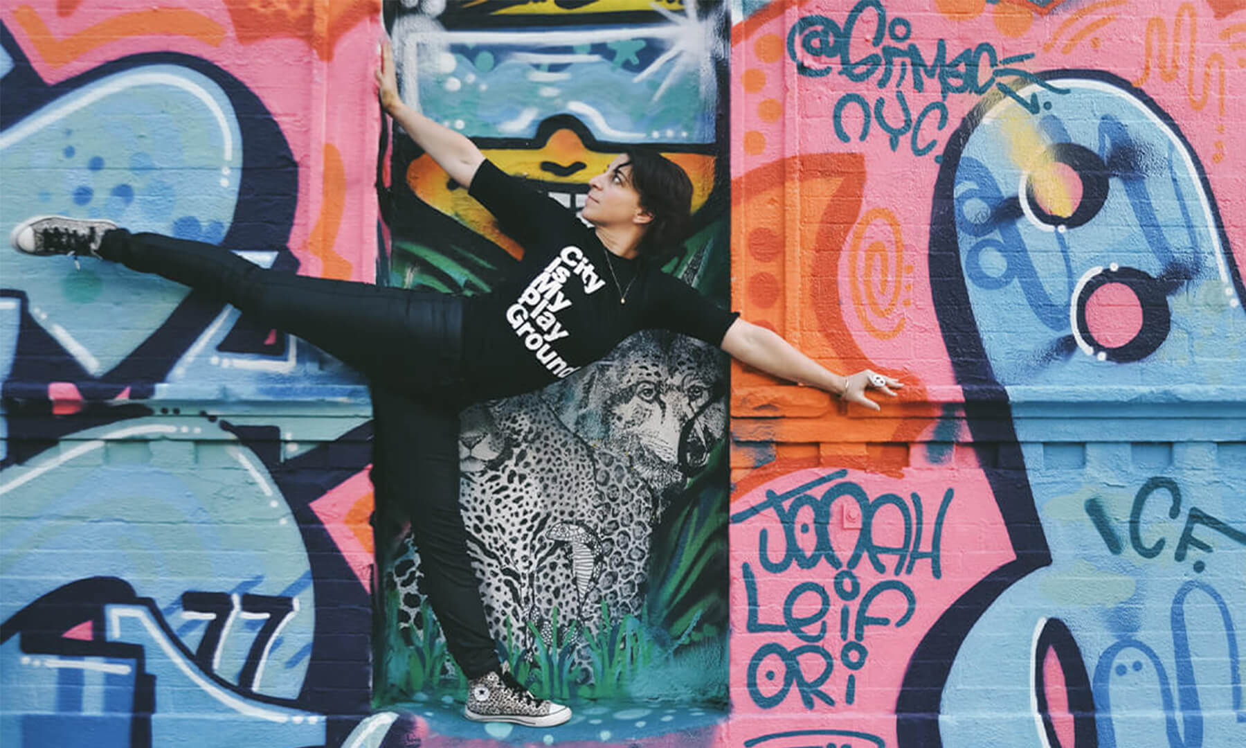 A person posing in front of a graffiti wall